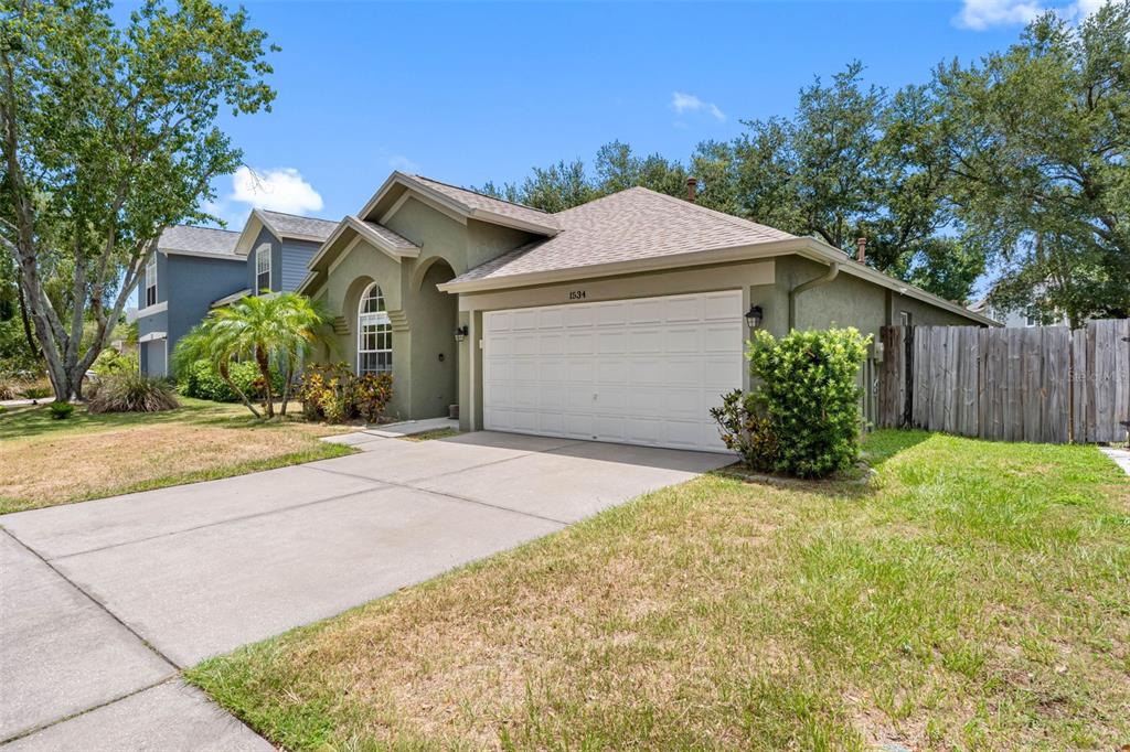 A single-story house with a white garage door, tan stucco exterior, and a concrete driveway — 1534 SCOTCH PINE DRIVE, BRANDON, FL