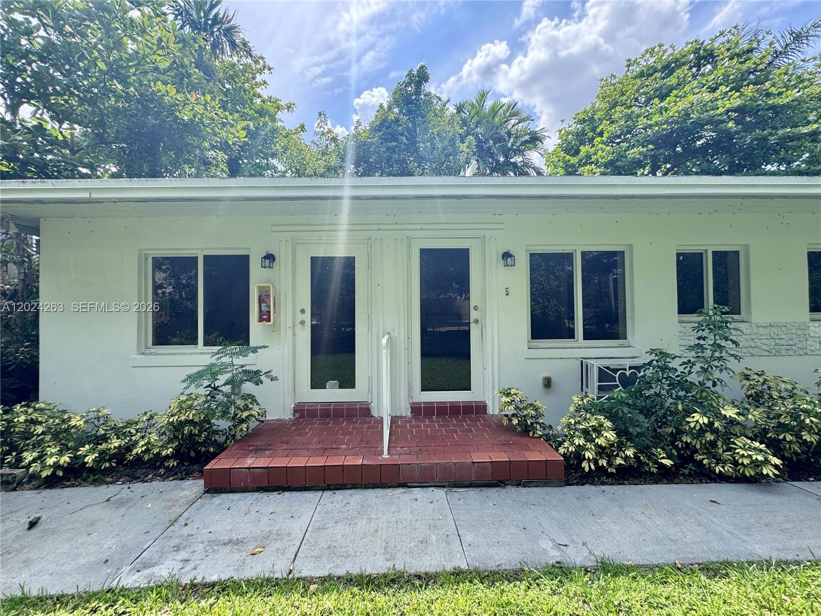 The exterior of a white, single-story building features two glass-paneled doors and a brick stoop — 8440 NE 1st Ave # 5, Miami FL 33138, MIAMI, FL