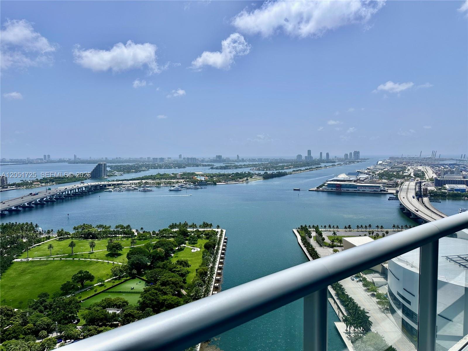 A high-angle view from a balcony overlooks a park, a waterway, and city bridges — 888 Biscayne Blvd # 3611, Miami FL 33132, MIAMI, FL