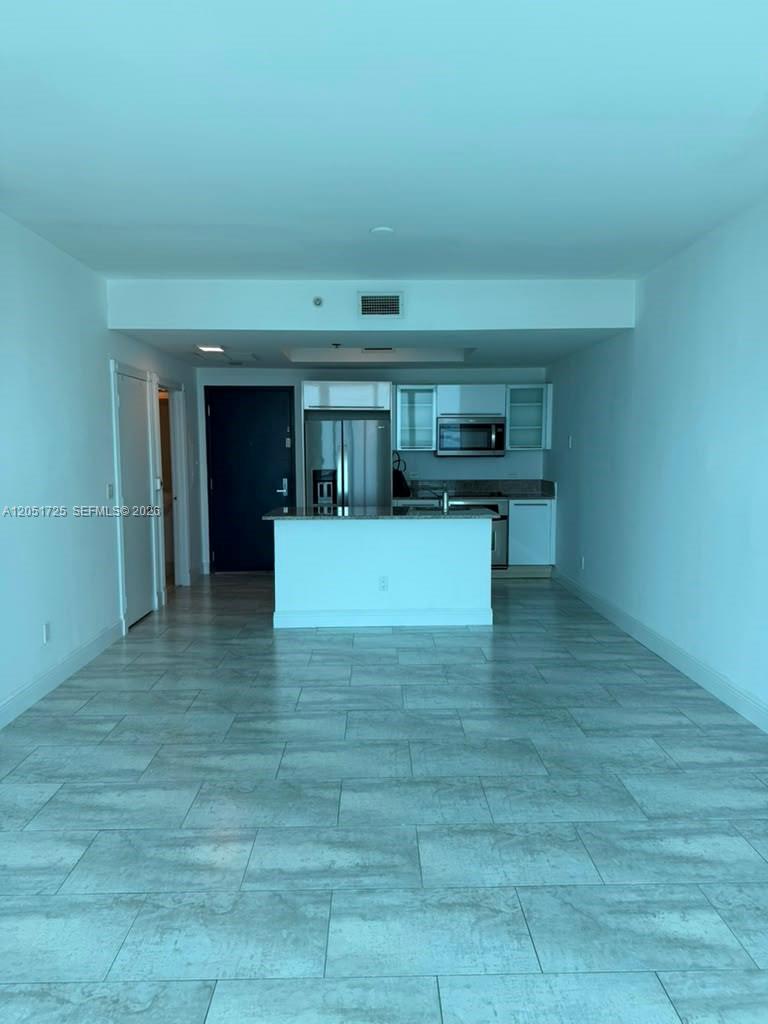 An open-concept kitchen with white cabinetry and an island overlooks a tiled living area — 888 Biscayne Blvd # 3611, Miami FL 33132, MIAMI, FL