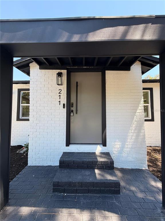 A front entrance features a gray door, white brick walls, and dark stone steps — 211 BAYSHORE DRIVE, ORLANDO, FL