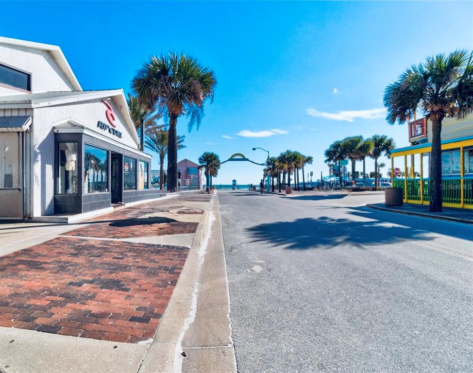 A street view shows a brick sidewalk, a Rip Curl store, and palm trees near beach — 510 FLAGLER AVENUE, NEW SMYRNA BEACH, FL