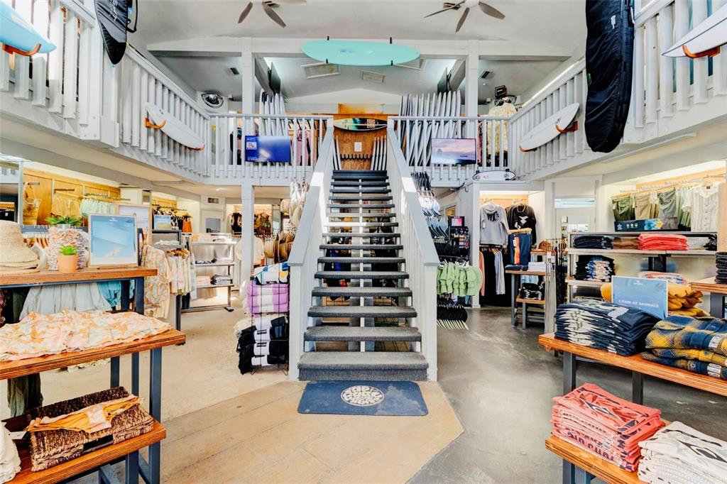 A retail surf shop features a central staircase leading to a lofted mezzanine level — 510 FLAGLER AVENUE, NEW SMYRNA BEACH, FL