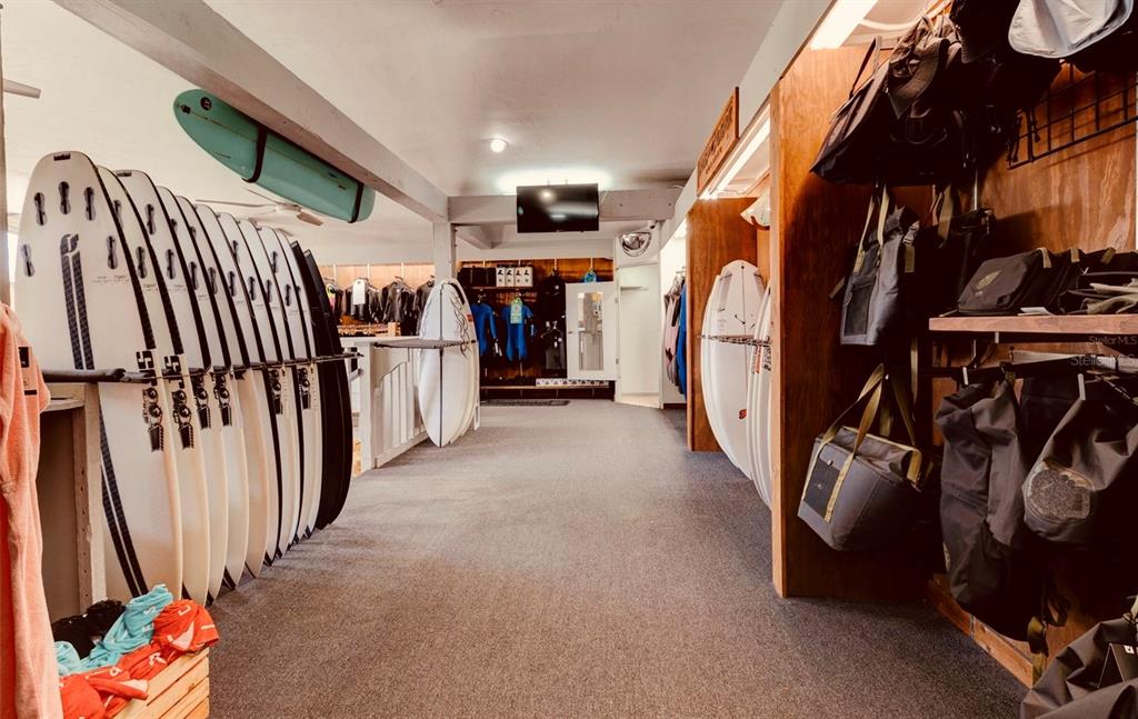 A surf shop interior features rows of surfboards on display and various gear for sale — 510 FLAGLER AVENUE, NEW SMYRNA BEACH, FL