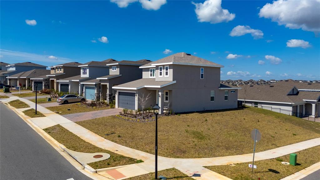 An aerial view shows a suburban street with several modern houses and manicured lawns — 2040 SUNSHINE PEAK DRIVE, MINNEOLA, FL