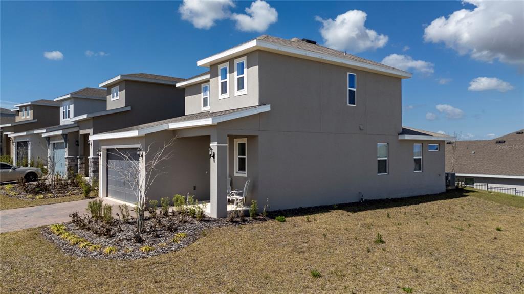 A two-story house with a tan stucco exterior, a gray garage, and a small front porch — 2040 SUNSHINE PEAK DRIVE, MINNEOLA, FL