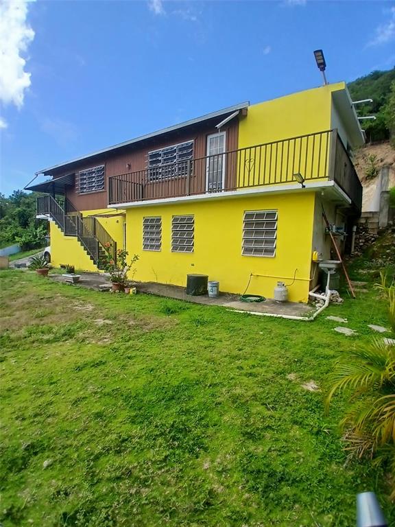 A two-story yellow house with a balcony and metal window shutters sits on a lawn — Carr. 127 KM 7.9, GUAYANILLA, PR