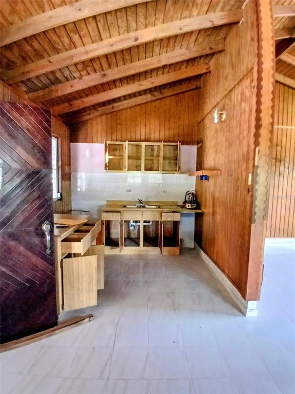 A kitchen with wood-paneled walls, exposed ceiling beams, and white tile flooring — Carr. 127 KM 7.9, GUAYANILLA, PR