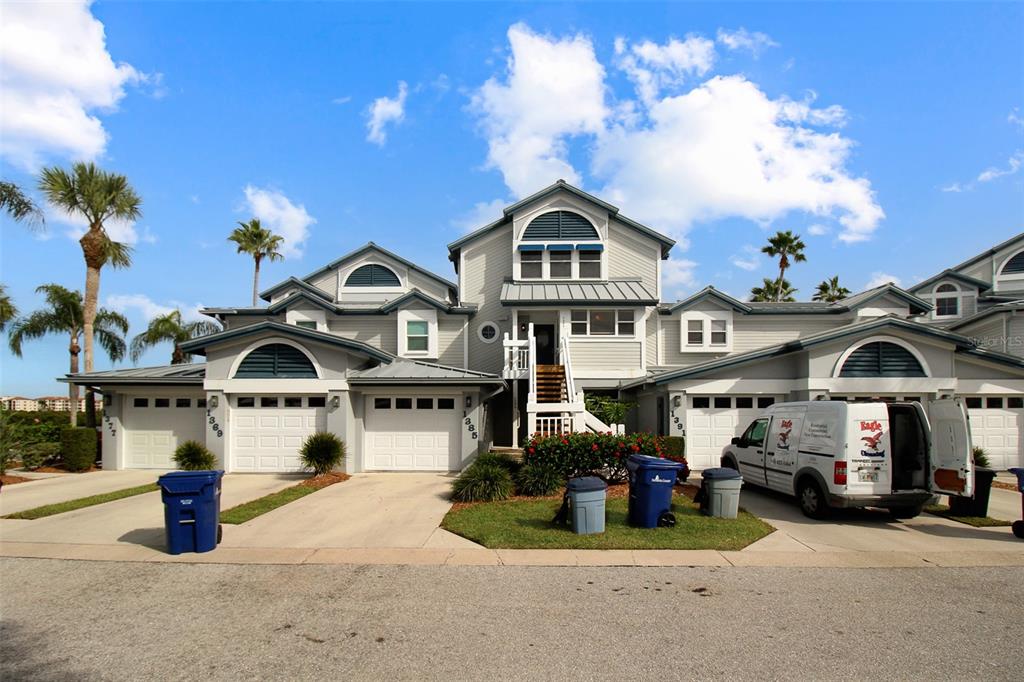 A multi-unit residential building with light gray siding, multiple garage doors, and a central staircase — 1391 SIESTA BAYSIDE DRIVE UNIT 1391-B, SARASOTA, FL