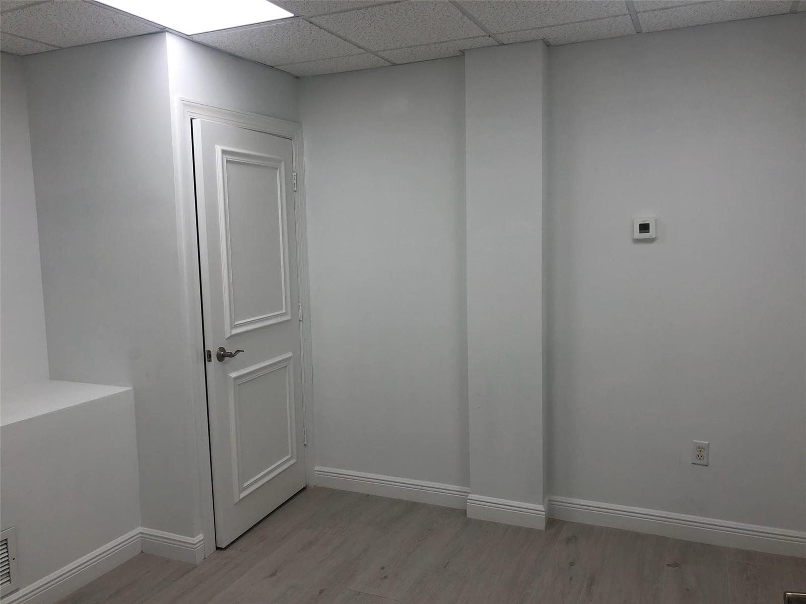 A room with light gray walls, wood-look flooring, a white door, and a central column — 6958 Griffin Road # 9, Davie FL 33314, DAVIE, FL