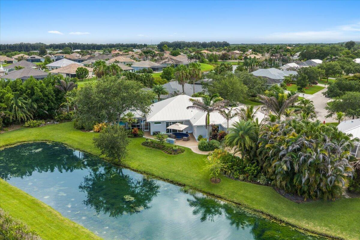 An aerial view of a house with a white roof beside a pond and landscaping — VERO BEACH, FL