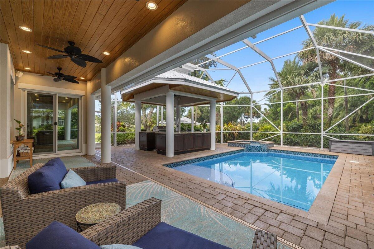 A covered patio features a swimming pool, a hot tub, and an outdoor kitchen area — VERO BEACH, FL