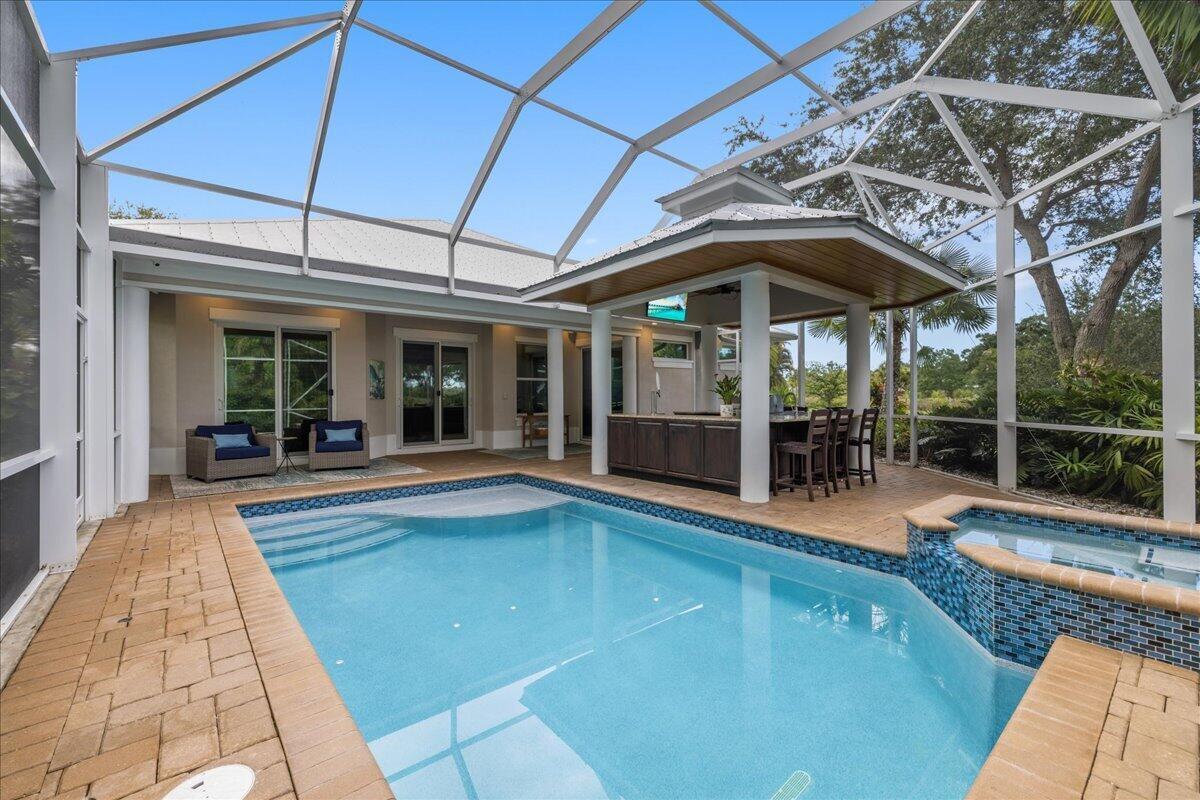 A screened-in patio features a swimming pool, a hot tub, and a covered outdoor bar — VERO BEACH, FL