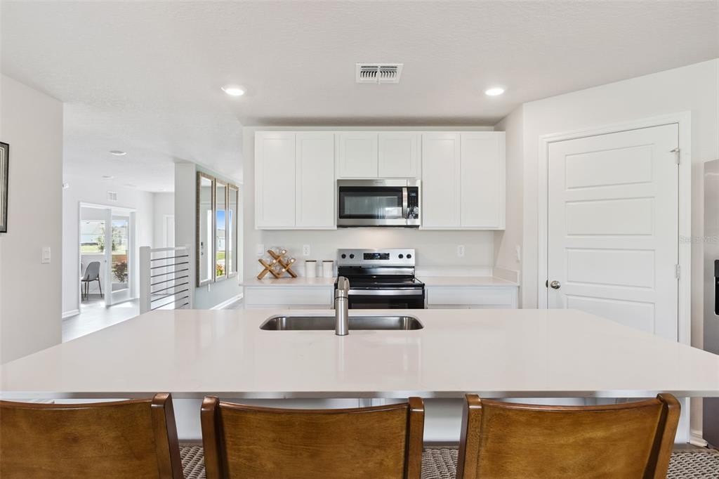 A kitchen features white cabinets, stainless steel appliances, and a large island with a sink — 227 SKYFIELD COURT, LADY LAKE, FL