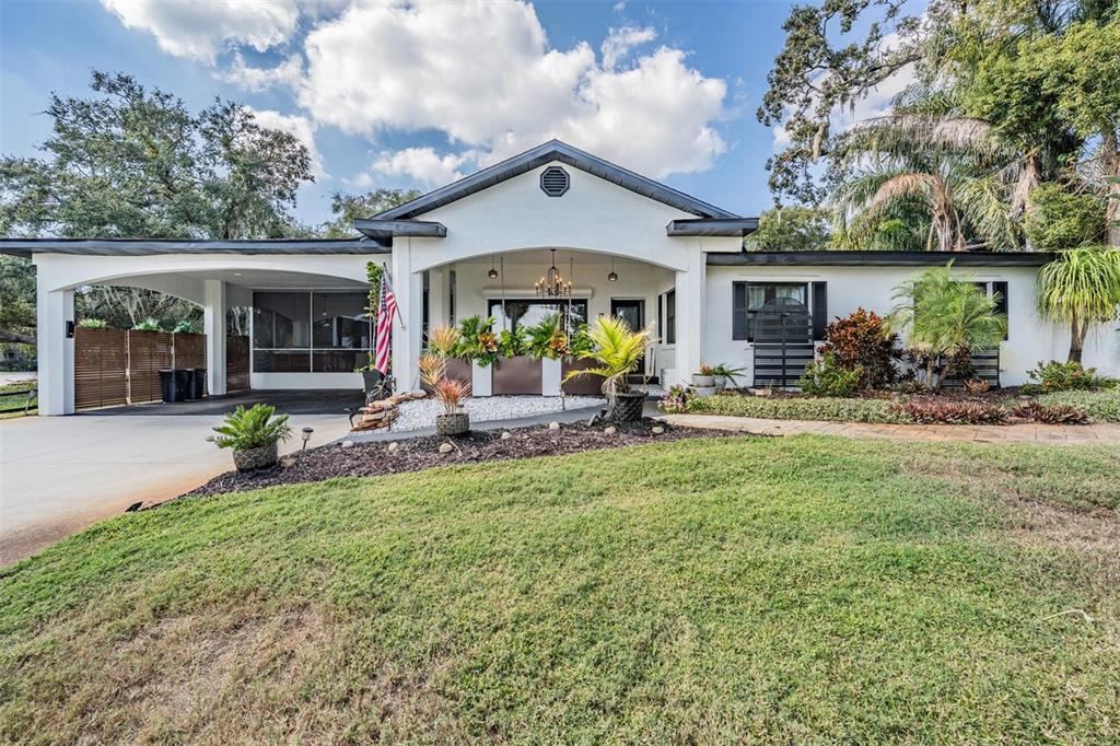 A white single-story house features a large front porch, a carport, and landscaped front yard — 302 WHITCOMB BOULEVARD, TARPON SPRINGS, FL