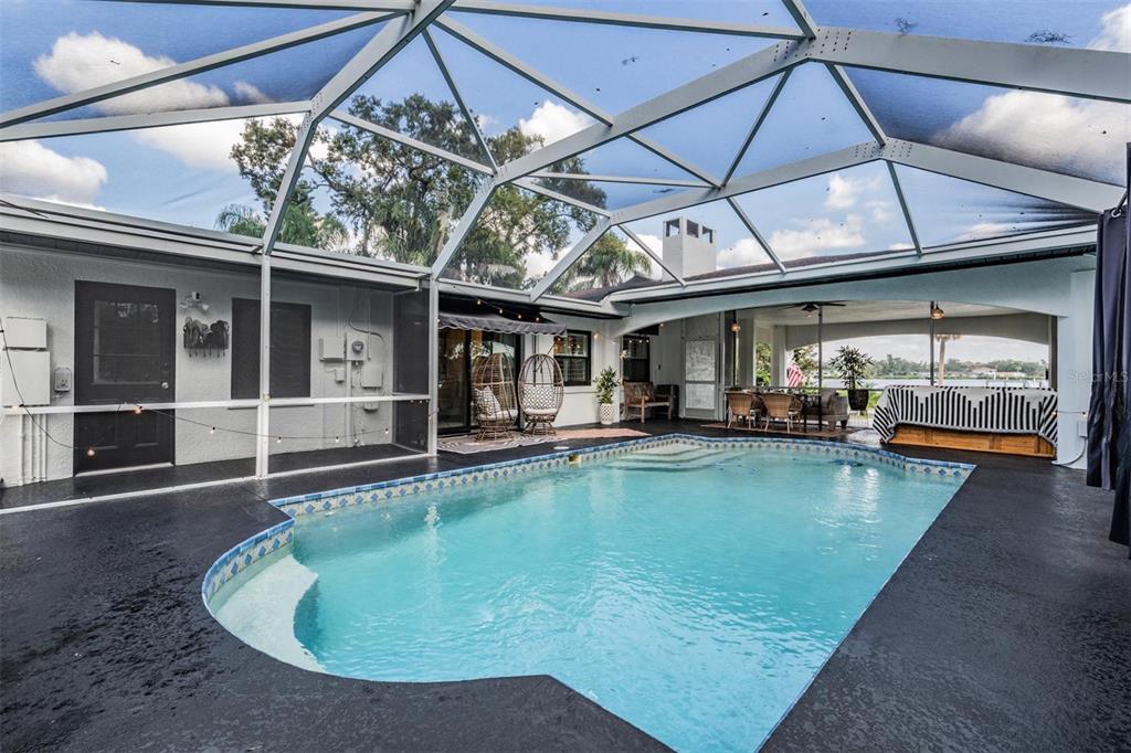 A screened-in patio features a swimming pool, dark flooring, and a covered outdoor dining area — 302 WHITCOMB BOULEVARD, TARPON SPRINGS, FL