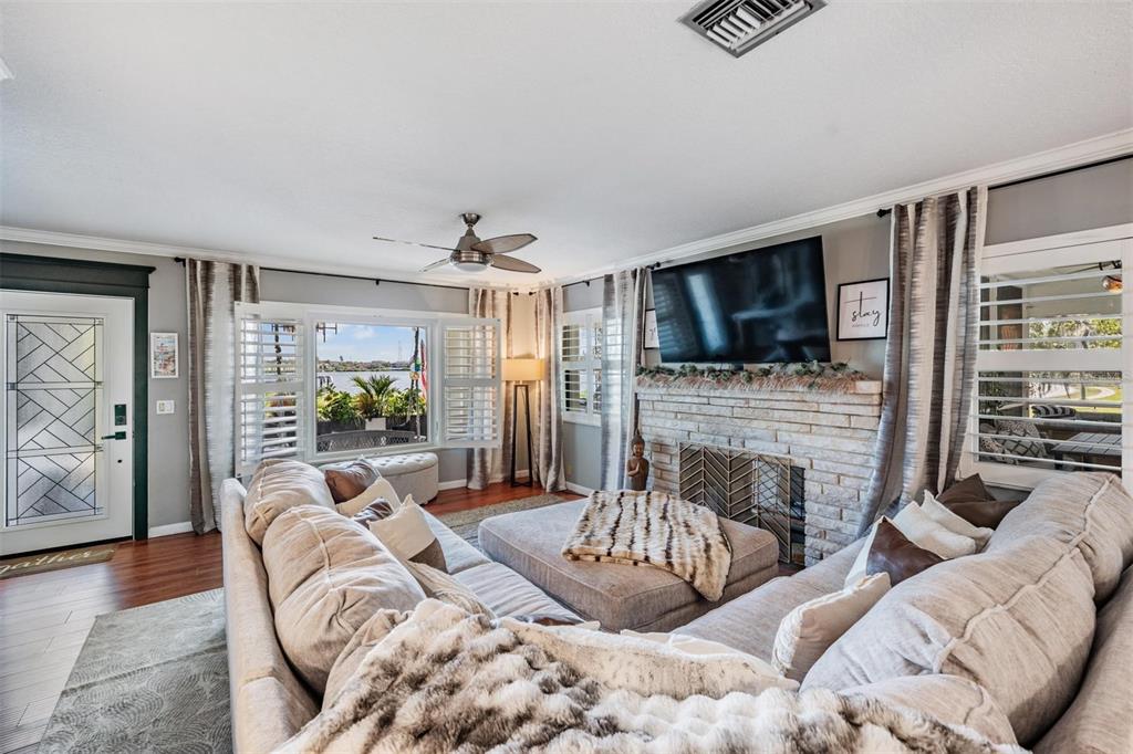 A living room features a stone fireplace, a large sectional sofa, and a waterfront view — 302 WHITCOMB BOULEVARD, TARPON SPRINGS, FL