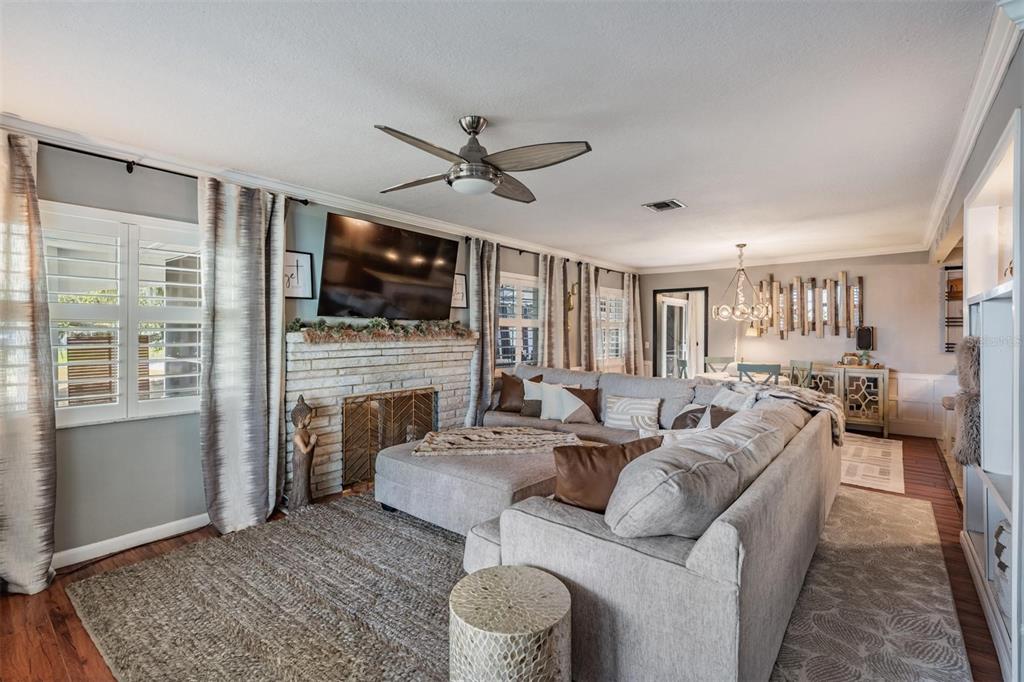 A living room features a brick fireplace, a large sectional sofa, and a ceiling fan — 302 WHITCOMB BOULEVARD, TARPON SPRINGS, FL