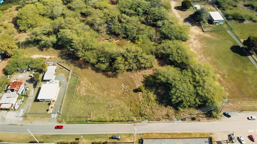 An aerial view shows a vacant lot with trees next to a building and road — BO. COROZO, COMBATE,  CARR. 301 KM HM 7.0, CABO ROJO, PR