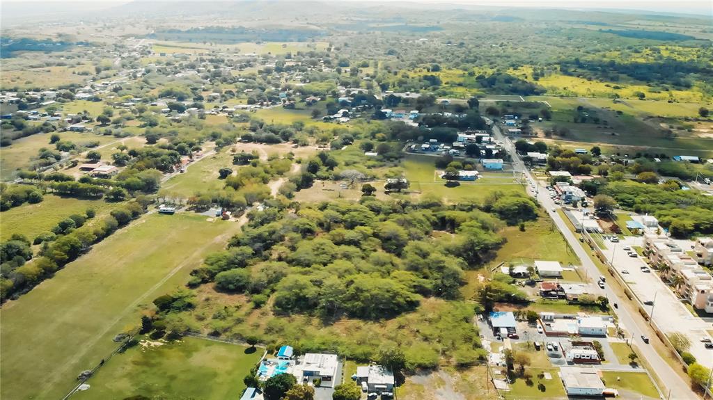An aerial view shows a rural landscape with scattered houses, trees, and a paved road — BO. COROZO, COMBATE,  CARR. 301 KM HM 7.0, CABO ROJO, PR