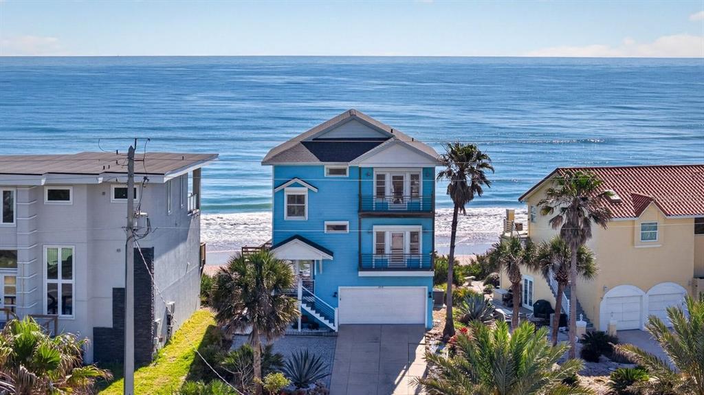 A blue three-story beach house sits between two other homes facing the ocean — 3319 N OCEAN SHORE BOULEVARD, FLAGLER BEACH, FL
