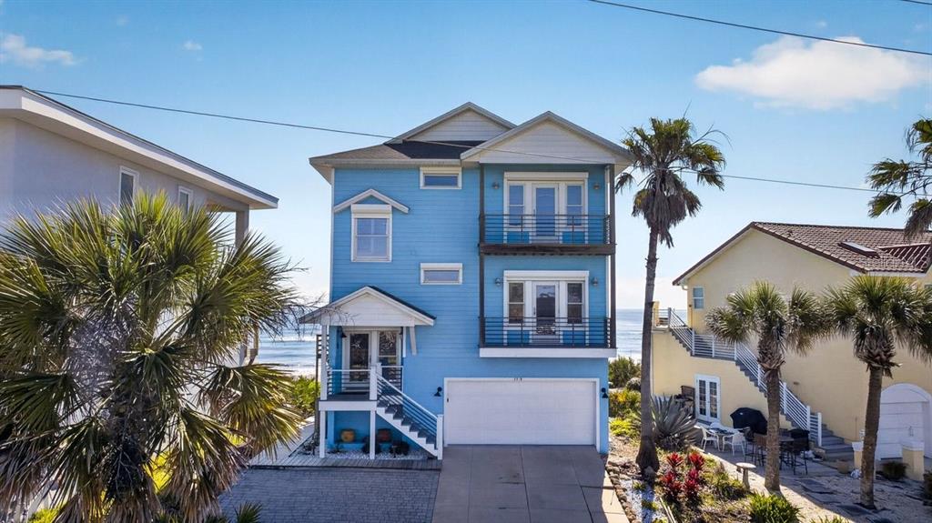 A three-story blue house with a two-car garage sits between two other homes — 3319 N OCEAN SHORE BOULEVARD, FLAGLER BEACH, FL