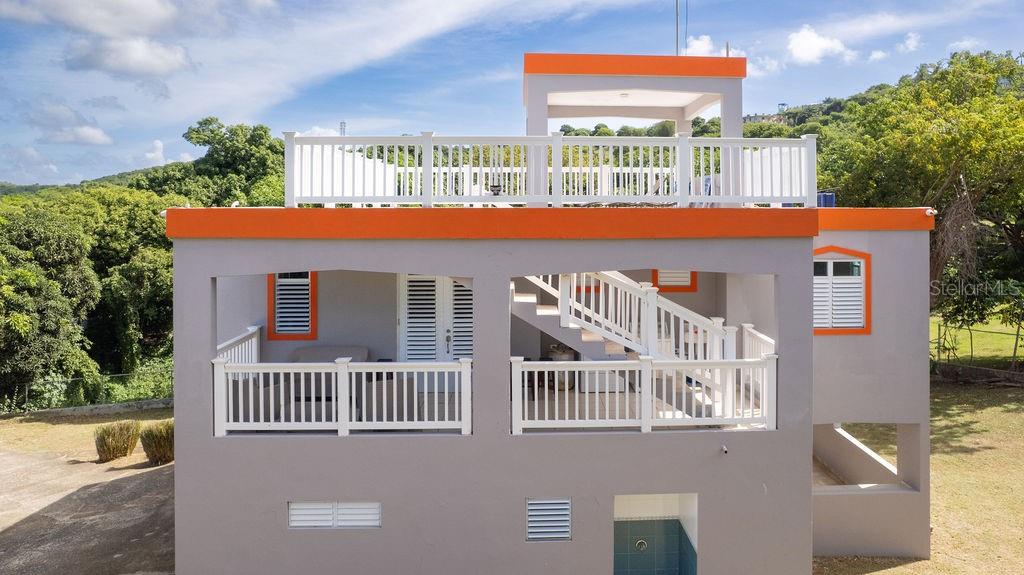 A two-story house with a grey exterior, orange trim, and a white-railed rooftop terrace — 78 HIDDEN PARADISE, VIEQUES, PR