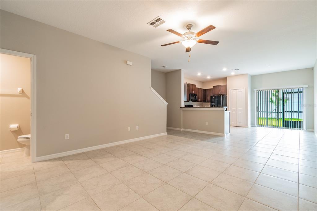 An open-concept living area features tile flooring, a ceiling fan, and an adjacent kitchen — 7221 SWEET ALYSSUM COURT, TAMPA, FL