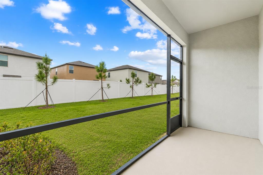 A screened-in patio overlooks a grassy backyard enclosed by a white vinyl fence — 7221 SWEET ALYSSUM COURT, TAMPA, FL