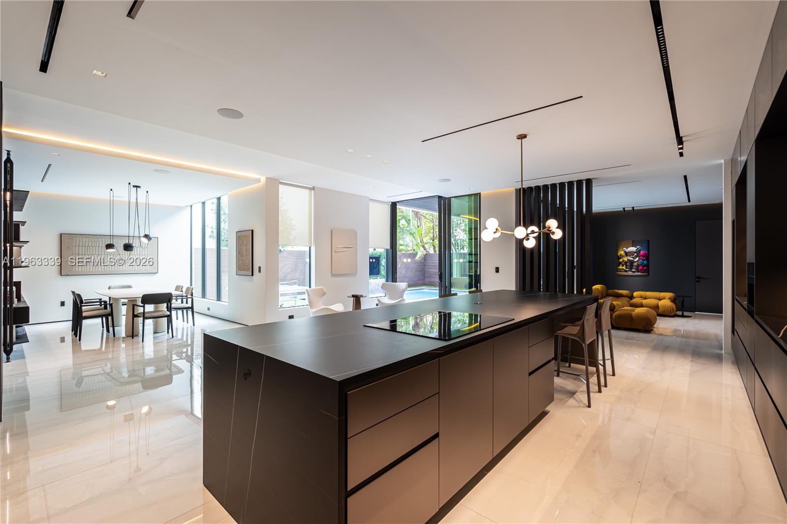 A modern kitchen features a large black island, white marble floors, and an adjacent dining area — 10540 NW 67th Ter, Doral FL 33178, DORAL, FL