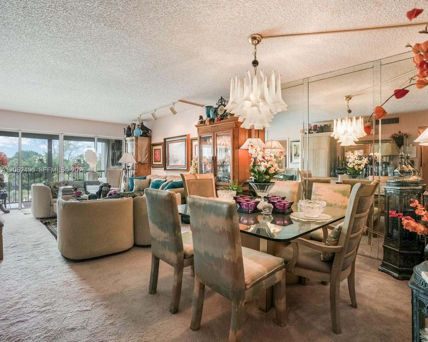 A dining area with a glass table and chairs sits before a mirrored wall — 3930 Inverrary Blvd # D, Lauderhill FL 33319, LAUDERHILL, FL