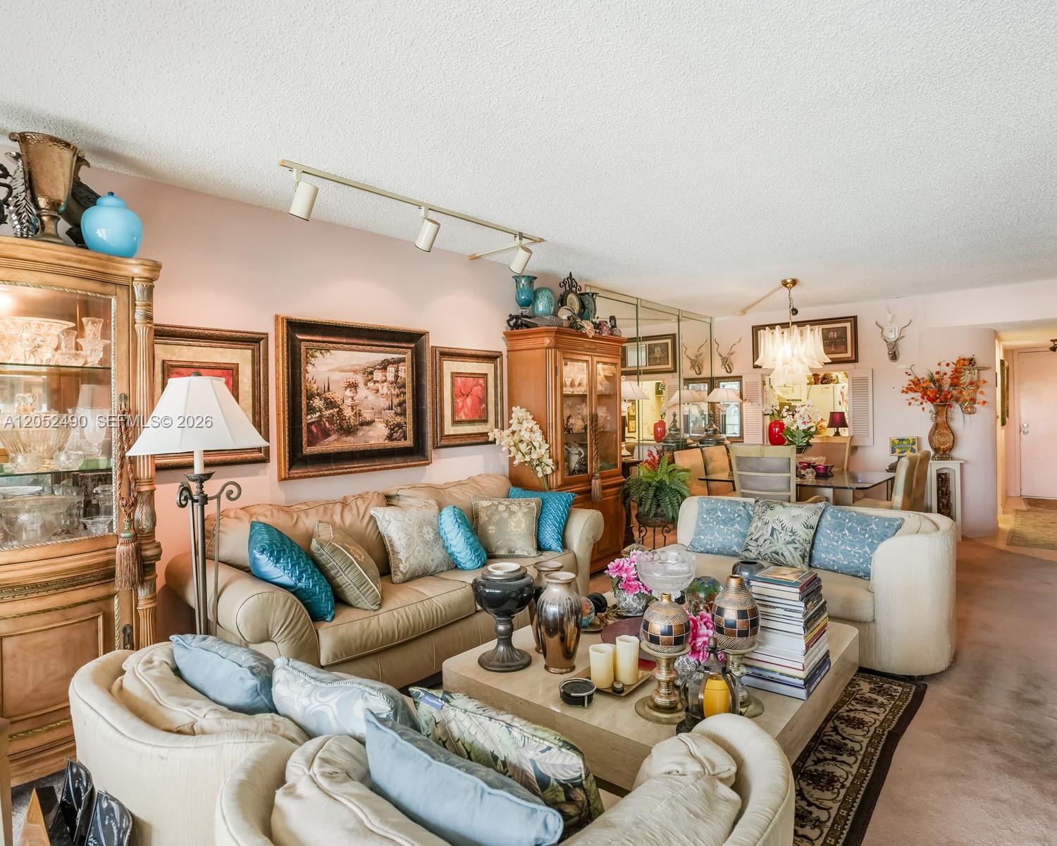 A living room features beige sofas, a coffee table, and a large wooden display cabinet — 3930 Inverrary Blvd # D, Lauderhill FL 33319, LAUDERHILL, FL