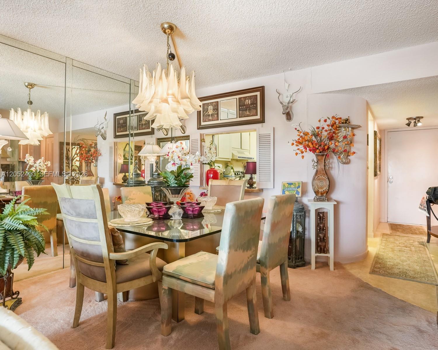 A dining room features a glass table, patterned chairs, a chandelier, and mirrored walls — 3930 Inverrary Blvd # D, Lauderhill FL 33319, LAUDERHILL, FL