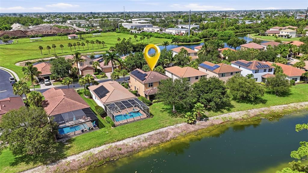 An aerial view shows a two-story house with a pool and solar panels near water — 2513 KEYSTONE LAKE DRIVE, CAPE CORAL, FL