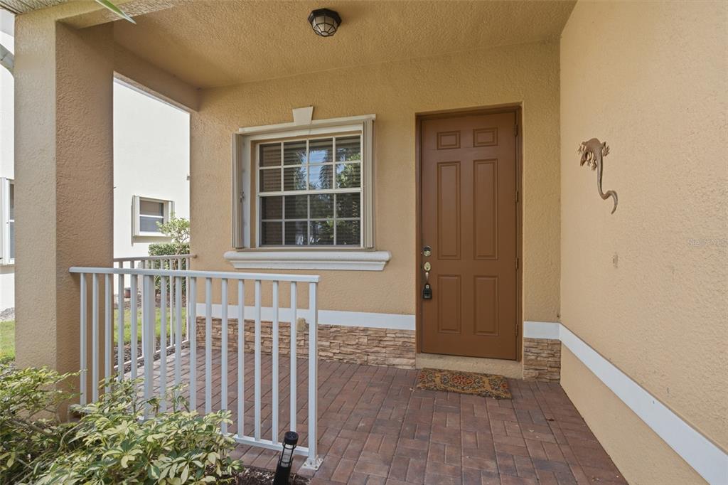 A covered front porch features a brown door, a window, and stone veneer accents — 2513 KEYSTONE LAKE DRIVE, CAPE CORAL, FL