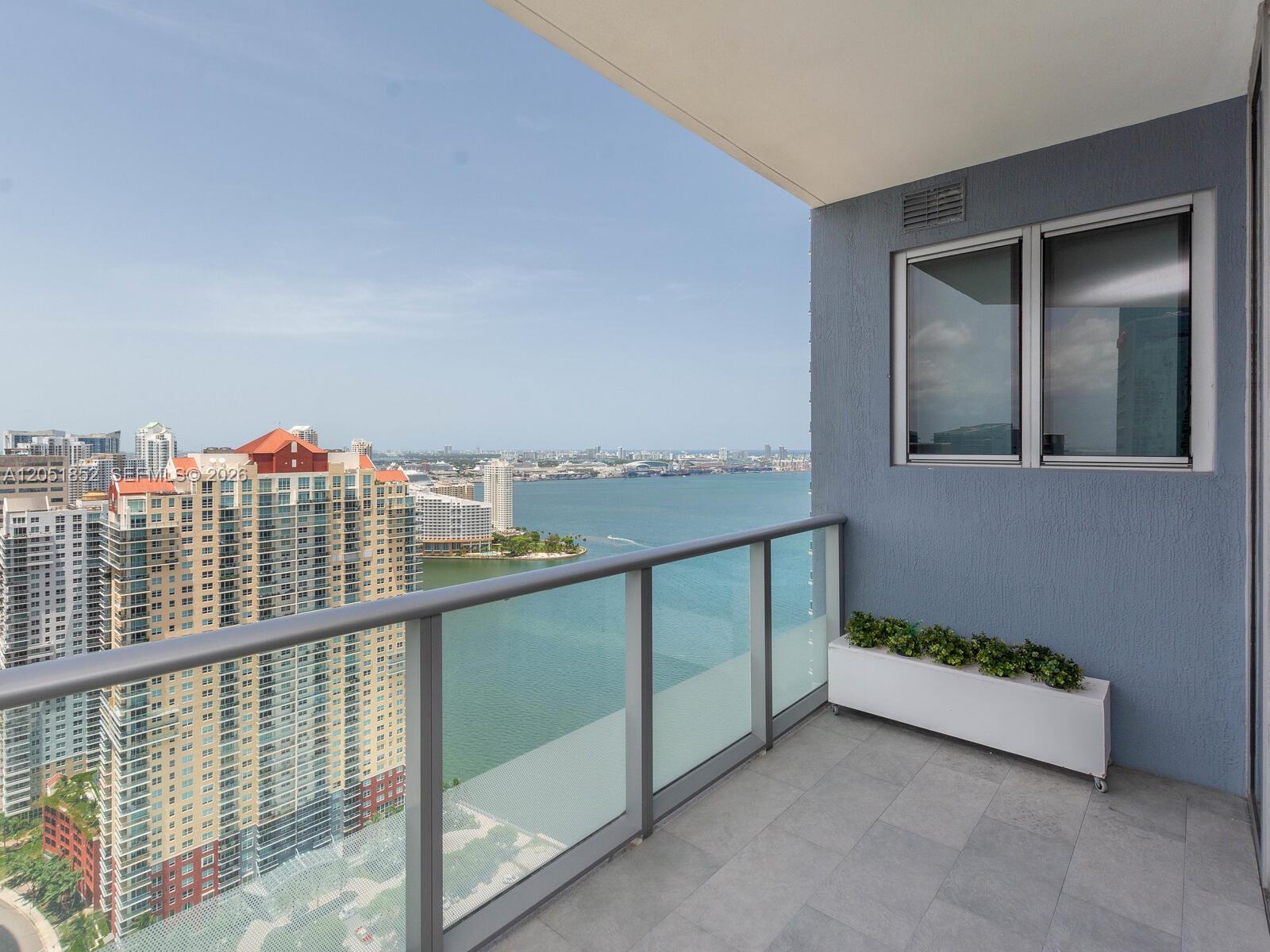 A balcony with a glass railing overlooks a bay and city skyline — 1300 Brickell Bay Dr # 3804, Miami FL 33131, MIAMI, FL