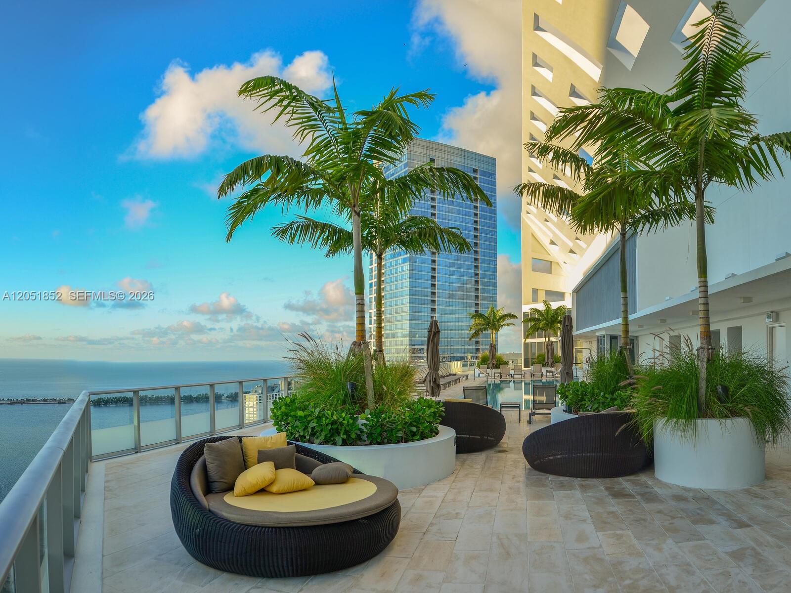 An outdoor terrace features lounge seating, potted palm trees, and a view of the ocean — 1300 Brickell Bay Dr # 3804, Miami FL 33131, MIAMI, FL