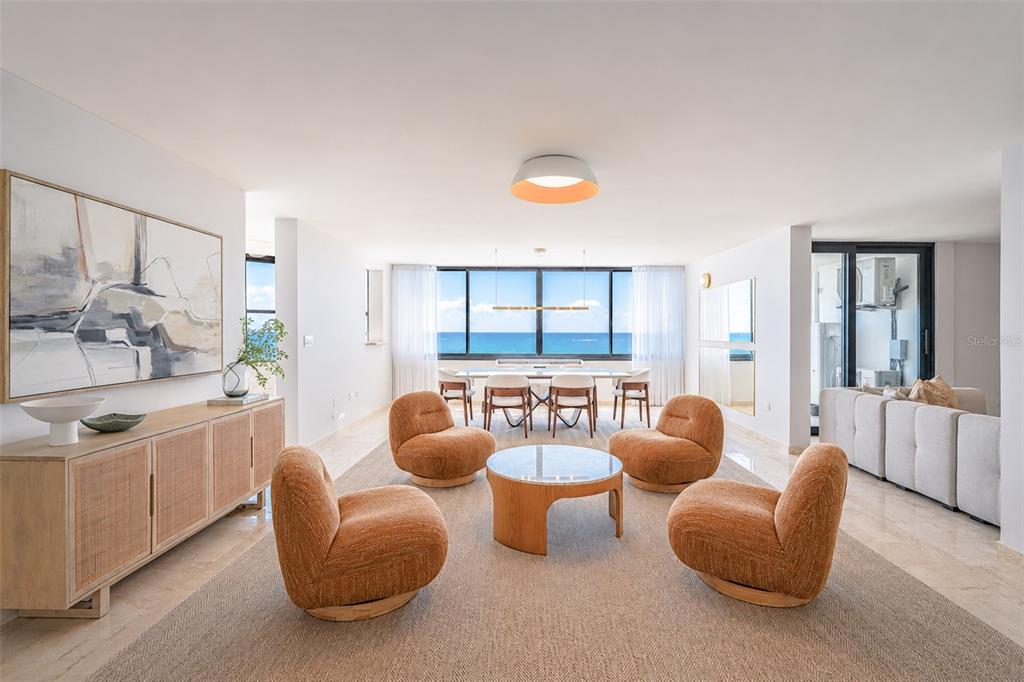 A bright, open-concept living and dining room features four orange chairs, a round table, and ocean views — 1 C. MANUEL RODRIGUEZ SERRA UNIT 601-A, SAN JUAN, PR
