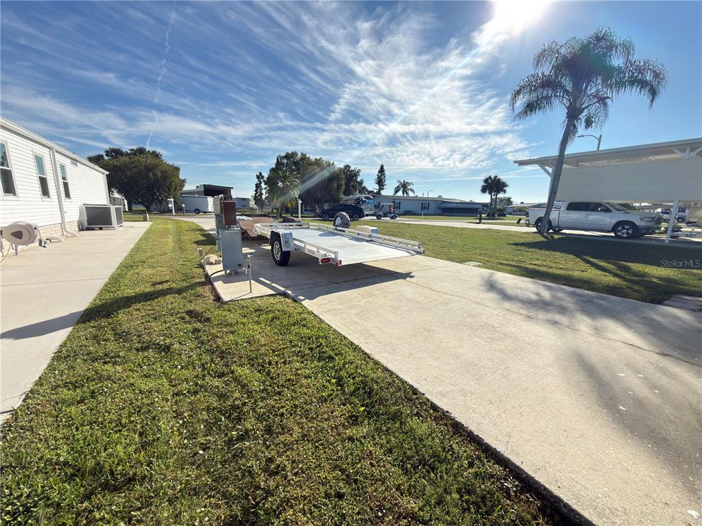 A flatbed trailer sits on a concrete driveway next to a mobile home — 4994 MOUNT OLIVE SHORES DRIVE, POLK CITY, FL