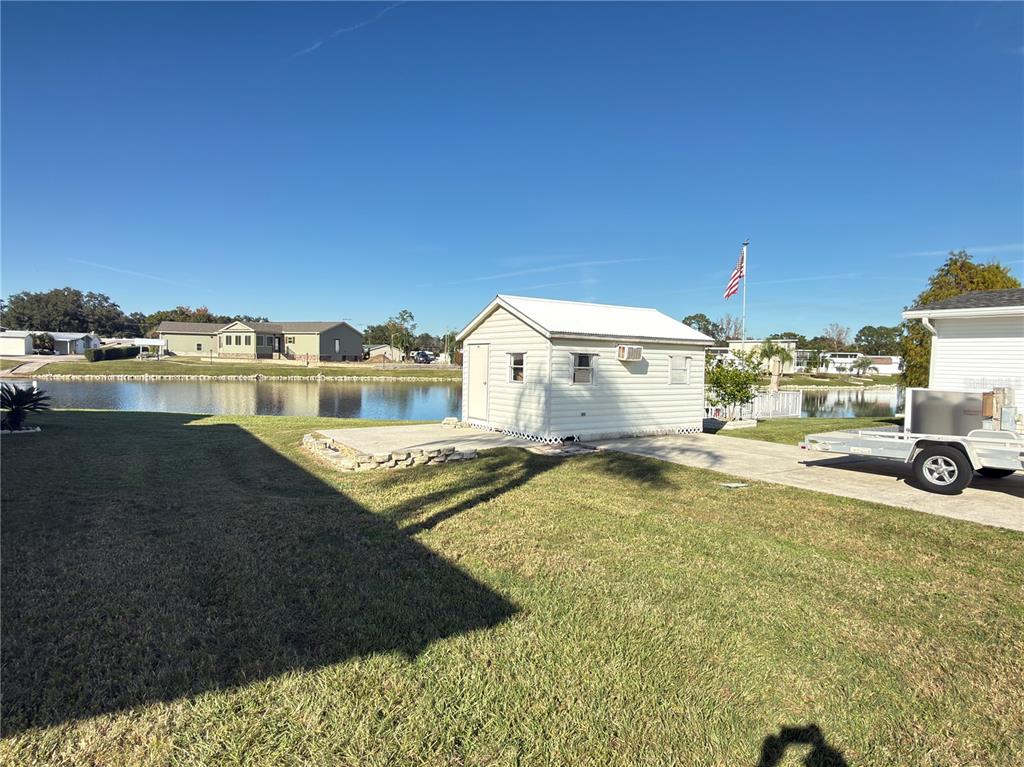 A small white shed sits on a concrete pad next to a lake — 4994 MOUNT OLIVE SHORES DRIVE, POLK CITY, FL