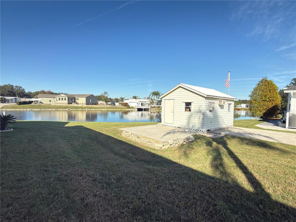 A small shed sits on a concrete pad next to a lawn overlooking a lake — 4994 MOUNT OLIVE SHORES DRIVE, POLK CITY, FL