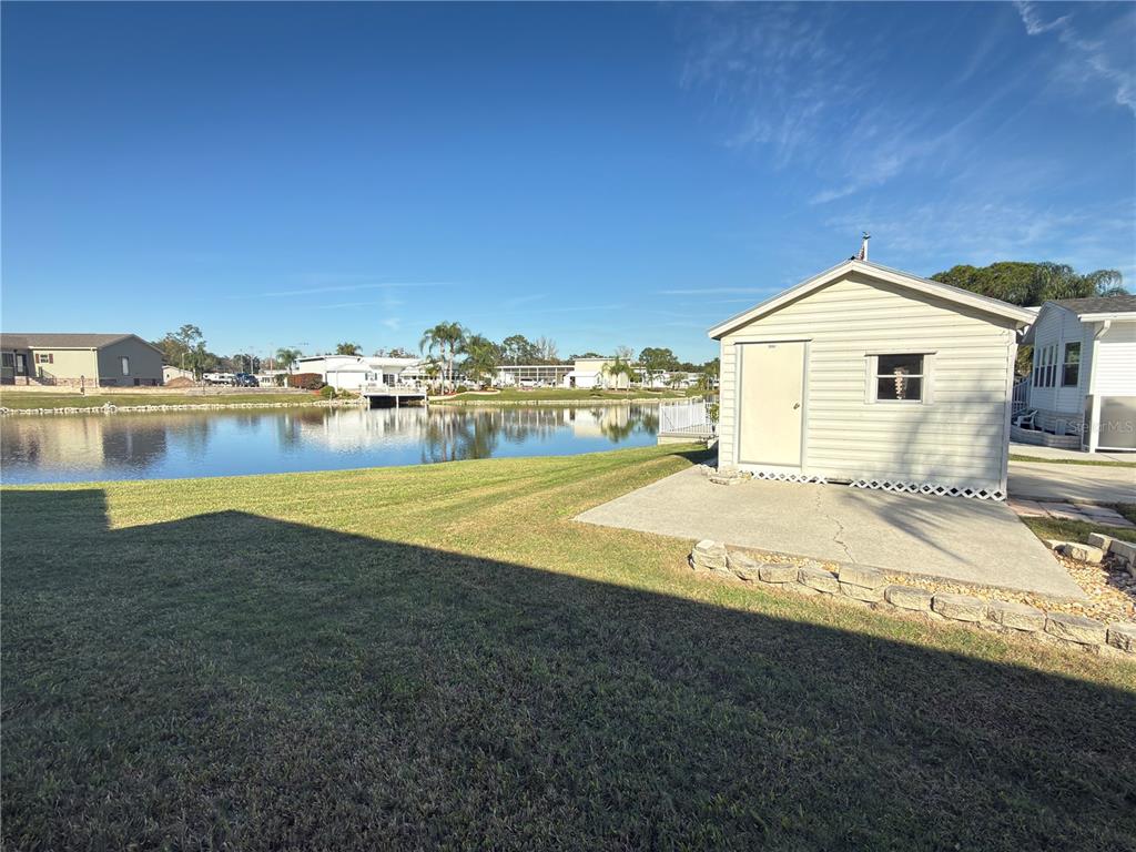 A backyard features a small shed on a concrete pad overlooking a pond — 4994 MOUNT OLIVE SHORES DRIVE, POLK CITY, FL