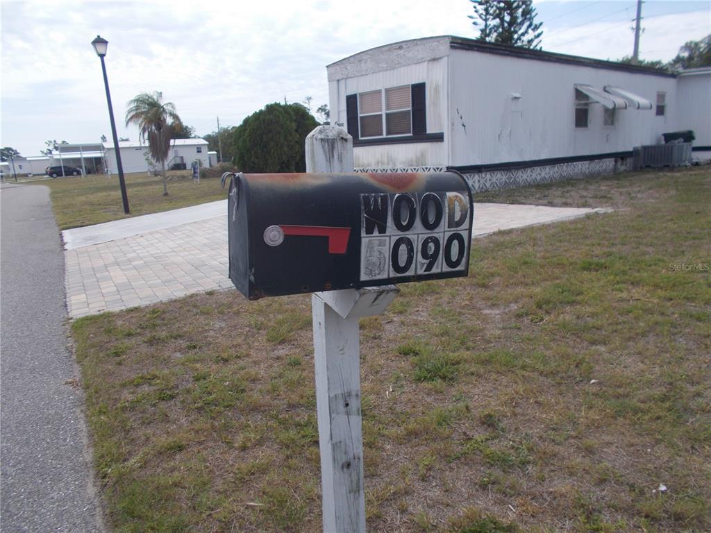 A weathered mailbox with the address 5090 stands in front of a mobile home — 5090 PALENA BOULEVARD, NORTH PORT, FL