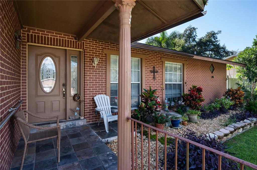 A brick house exterior features a covered front porch with tile flooring and a brown door — 520 SAN SEBASTIAN PRADO, ALTAMONTE SPRINGS, FL