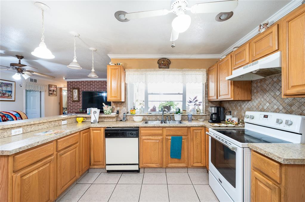 A kitchen features oak cabinets, laminate countertops, a white stove, and tile flooring — 520 SAN SEBASTIAN PRADO, ALTAMONTE SPRINGS, FL