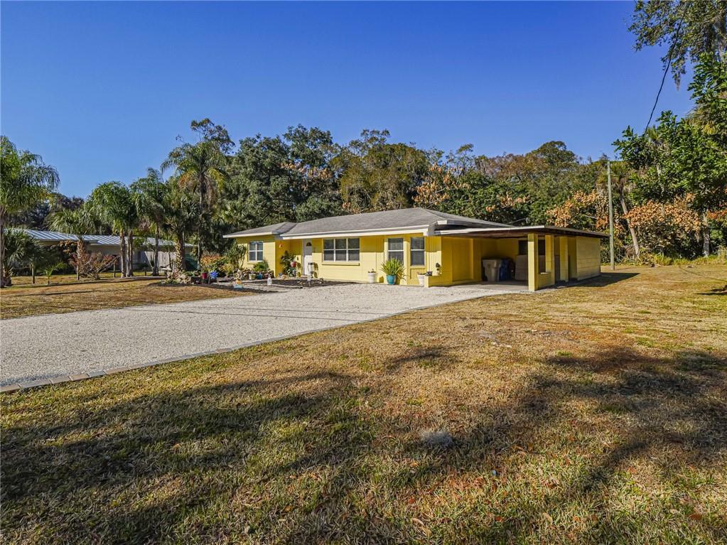 A yellow single-story house with a gravel driveway and an attached carport — 2049 50th Avenue, Vero Beach FL 32966, VERO BEACH, FL
