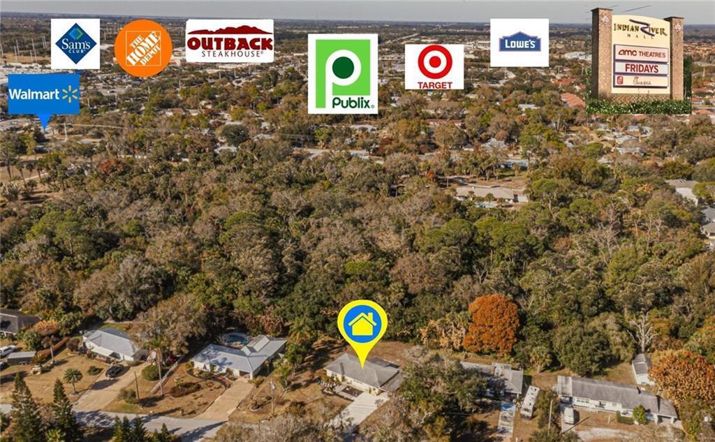 An aerial view shows a residential house surrounded by trees near several commercial shopping centers — 2049 50th Avenue, Vero Beach FL 32966, VERO BEACH, FL