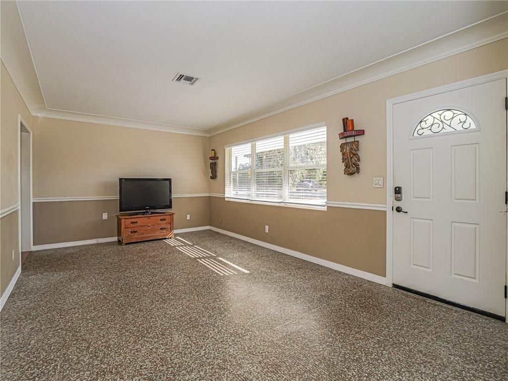 A living room features two-tone walls, a speckled floor, a television on a dresser, and windows — 2049 50th Avenue, Vero Beach FL 32966, VERO BEACH, FL