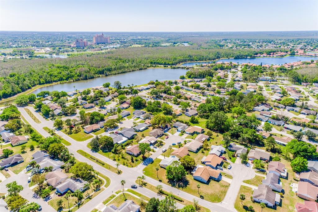 An aerial view shows a residential neighborhood with houses, green trees, and a large lake — 10330 LICORICE WAY, ORLANDO, FL