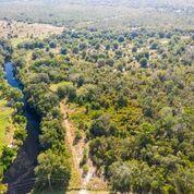 An aerial view shows a narrow river flowing alongside a dense, wooded area of land — 1055 Lake Josephine Drive, Sebring FL 33875, SEBRING, FL